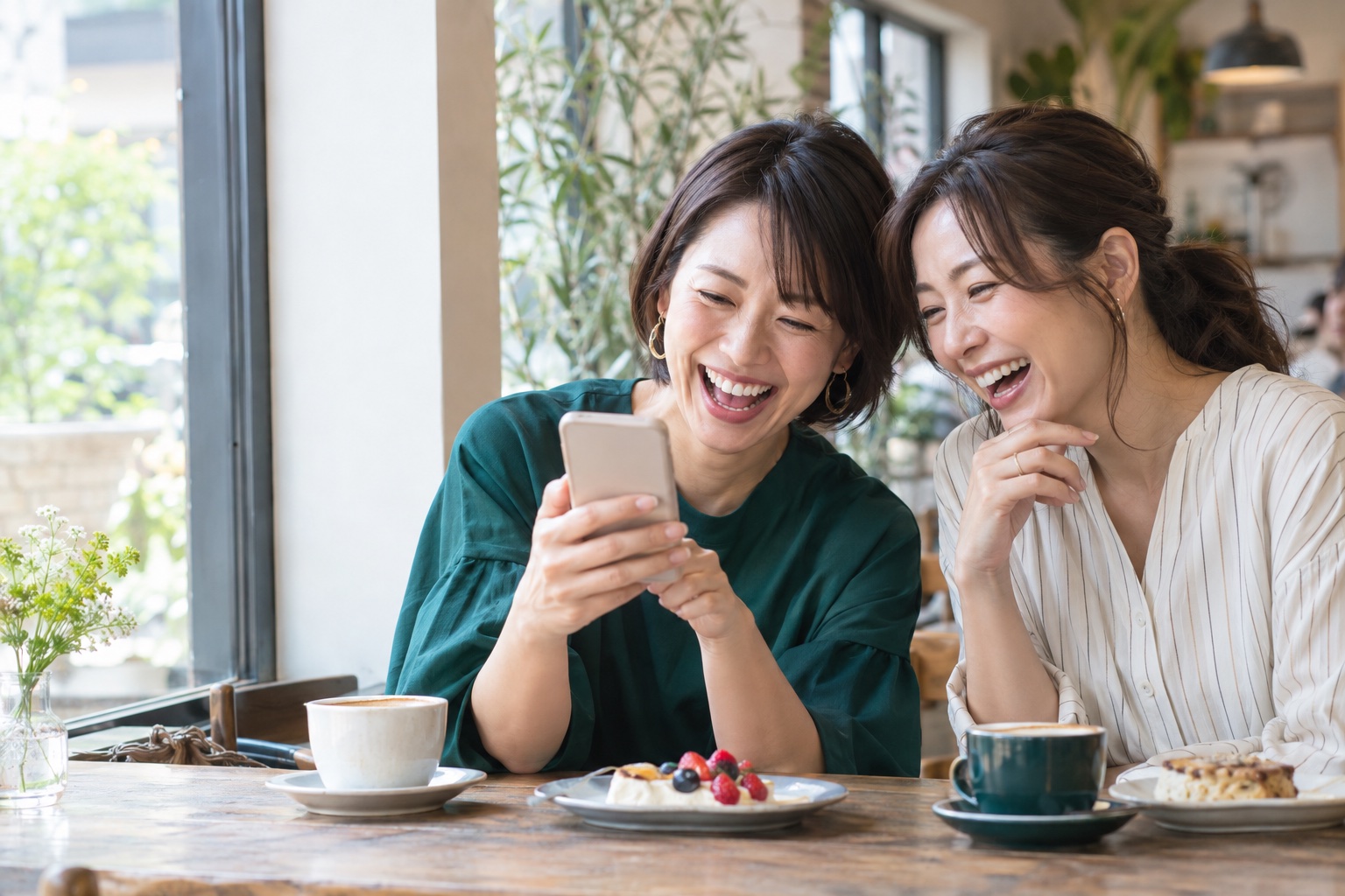 スマートフォンの画面を見せ合って笑う二人。